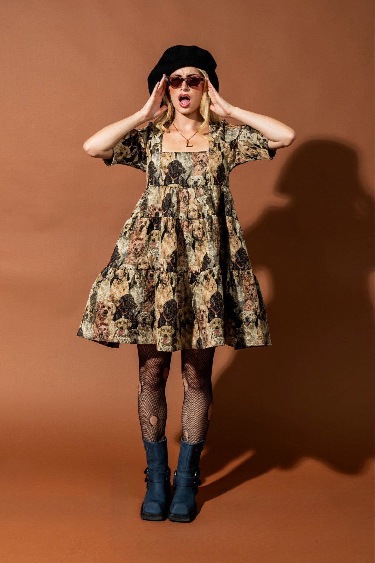 Woman wearing a patterned dress and black boots against a brown background