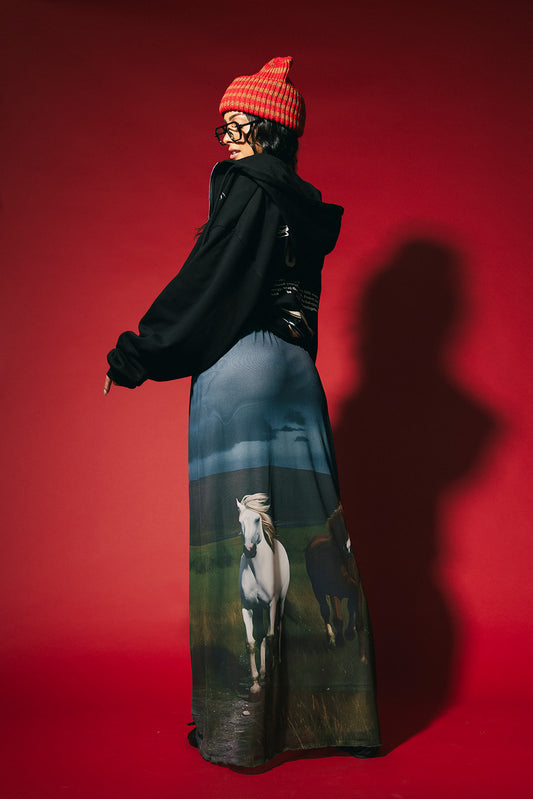 Person wearing a long dress with a horse print against a red background