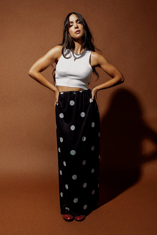 Woman wearing a black mesh maxi skirt with white polka dots against a brown background