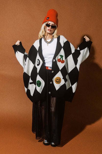 Person wearing a black and white checkered cardigan with colorful designs on an orange background