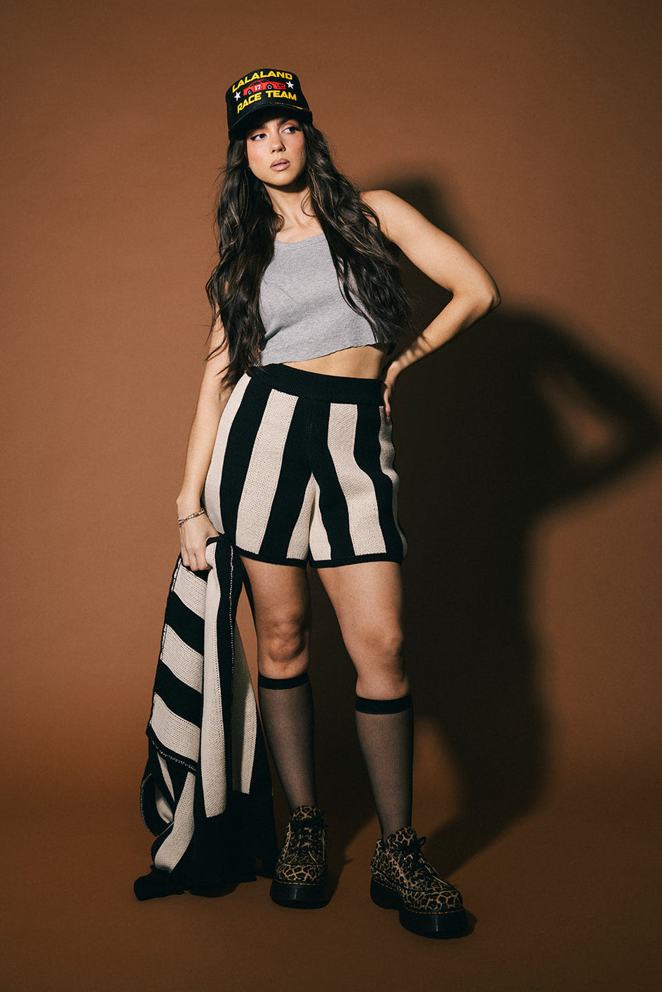 Woman wearing a striped outfit with a cap against a brown background