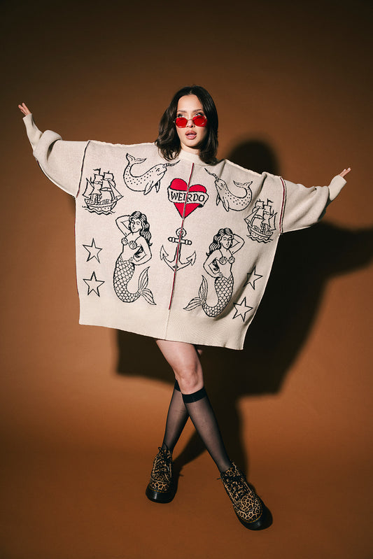 Person wearing a graphic sweater with various tattoo designs on a brown background