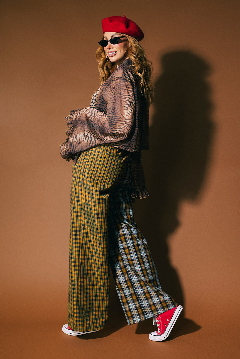 Person wearing plaid half and half trousers on a brown background