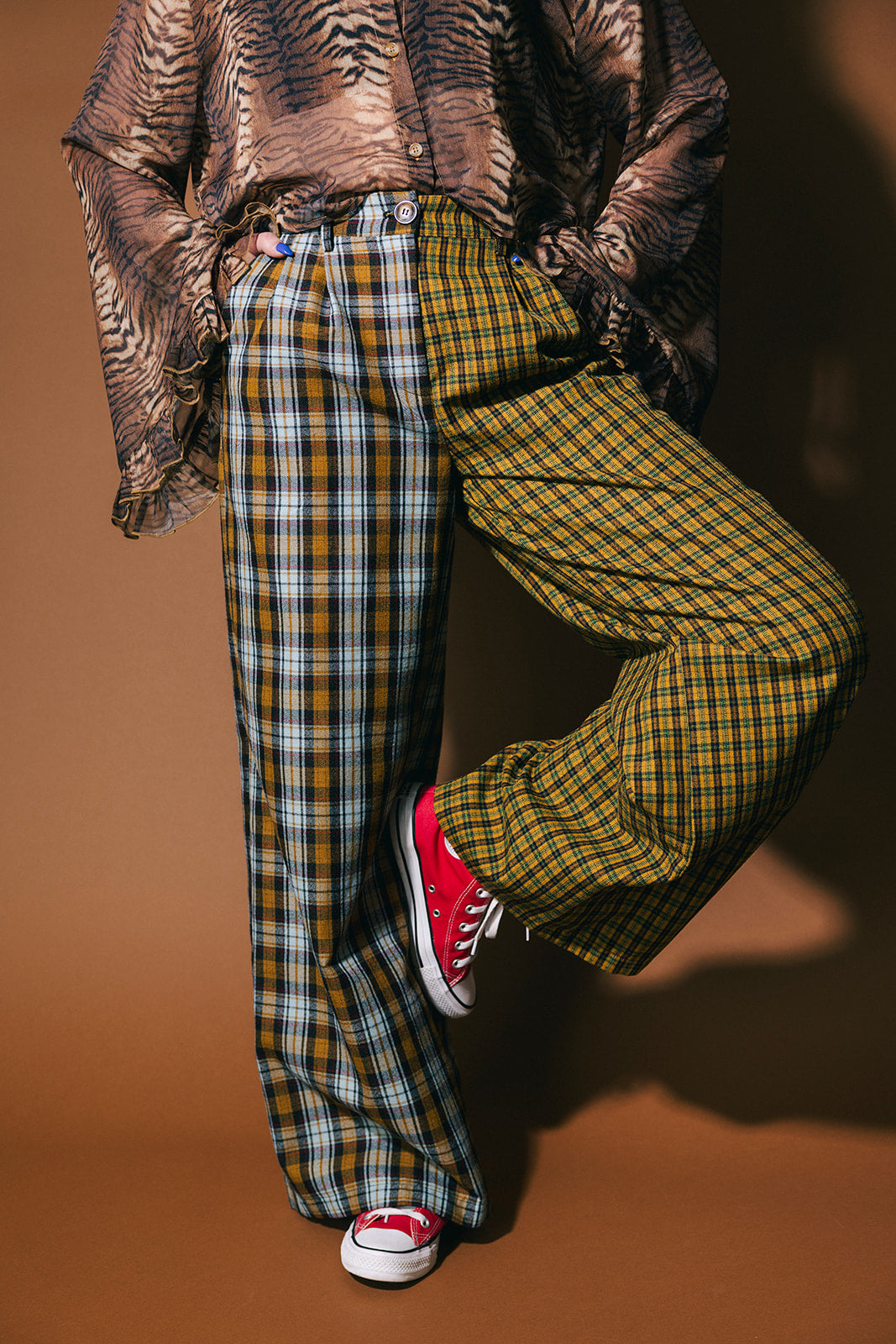 Person wearing plaid half and half trousers on a brown background
