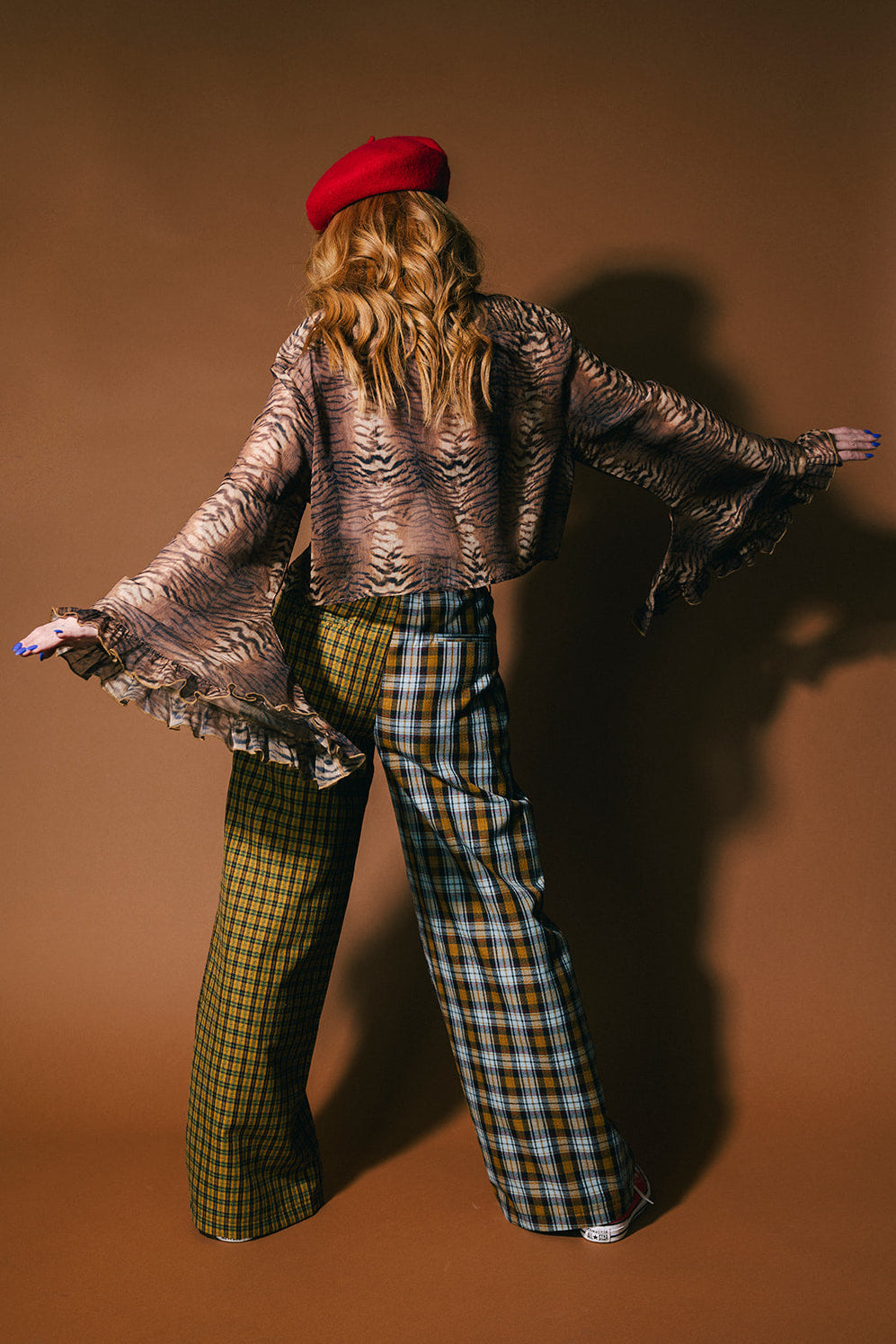 Person wearing plaid half and half trousers on a brown background