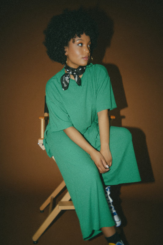 photo of girl wearing green ribbed matching set. The top is long and oversized with high side slits. Pants are cropped and wide leg with an elastic waistband.