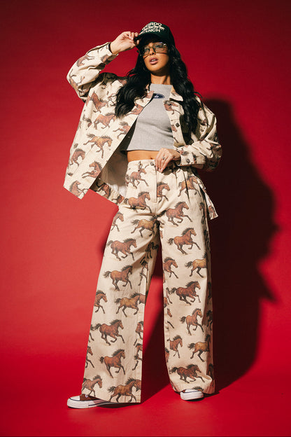 Person wearing a white denim jacket with a horse pattern on a red background