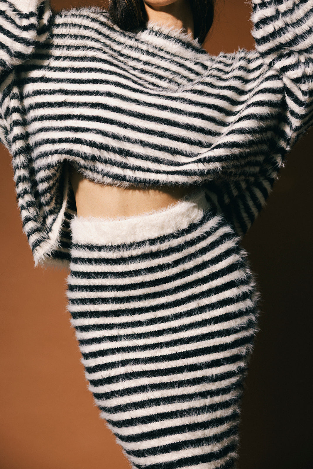 Close up of a black and white stripe sweater and skirt with fuzzy texture and elastic wasitband.