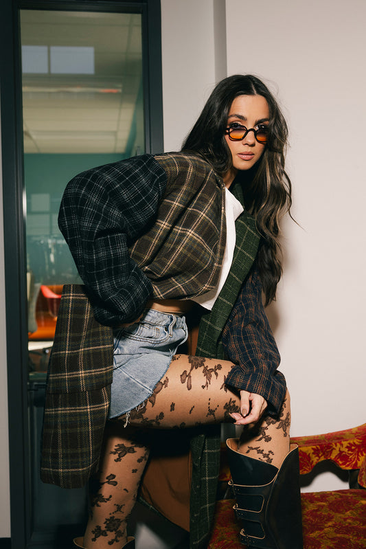 Woman wearing a patchwork plaid car coat and patterned tights in an indoor setting