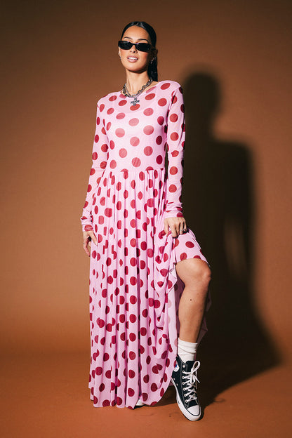 Woman wearing a pink polka dot dress against a brown background