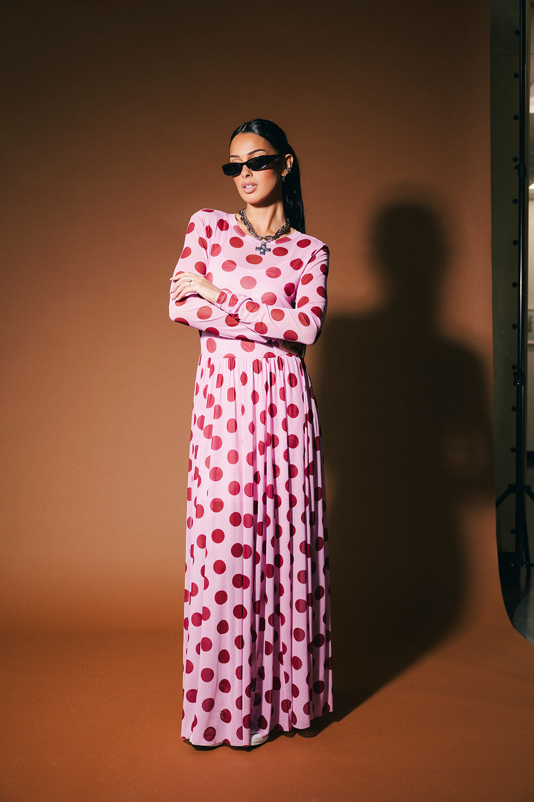 Woman wearing a pink polka dot dress against a brown background