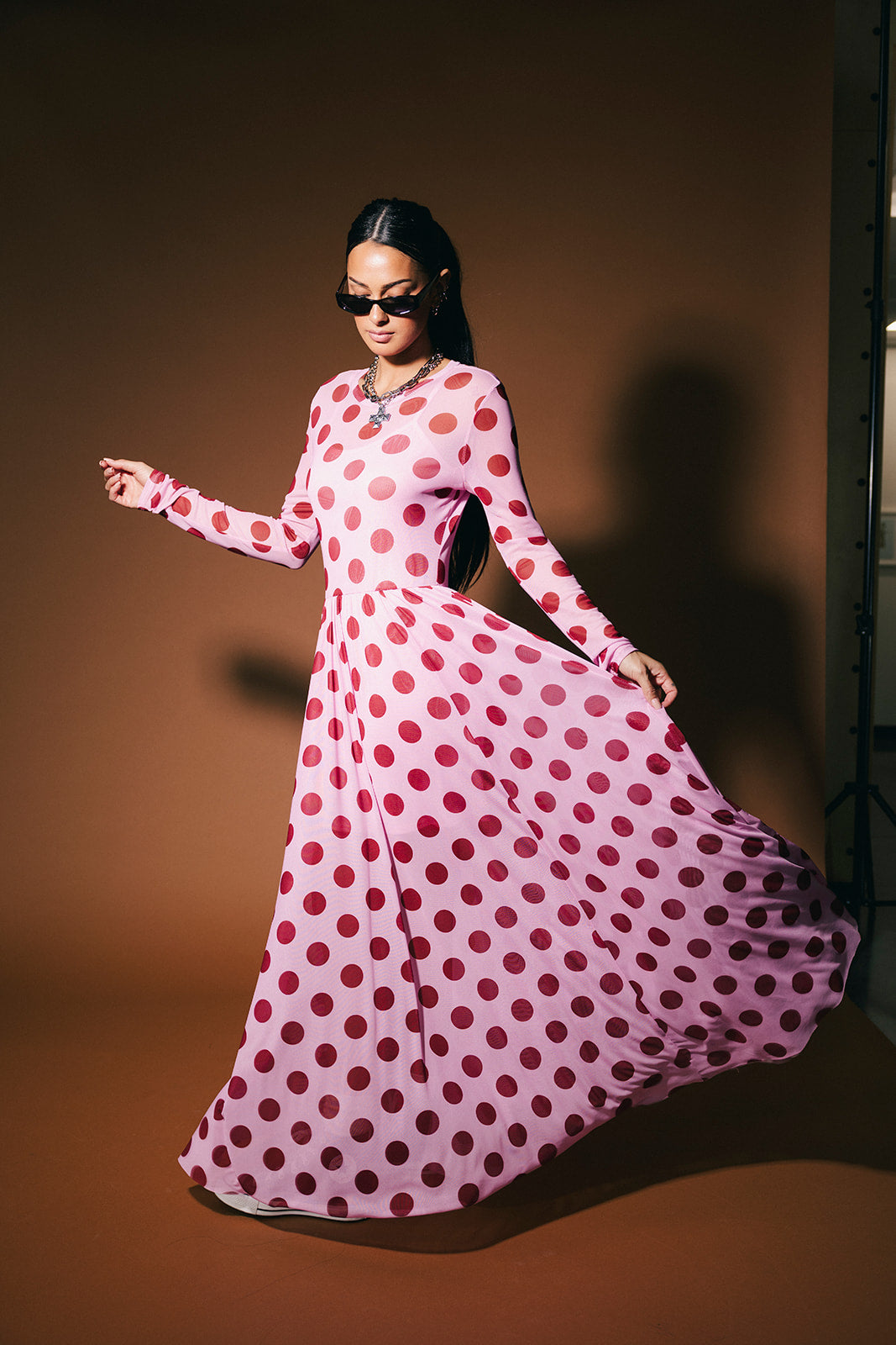 Woman wearing a pink polka dot dress against a brown background