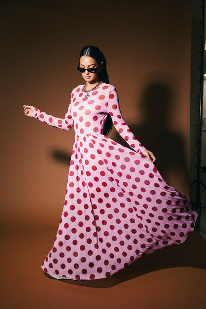 Woman wearing a pink polka dot dress against a brown background