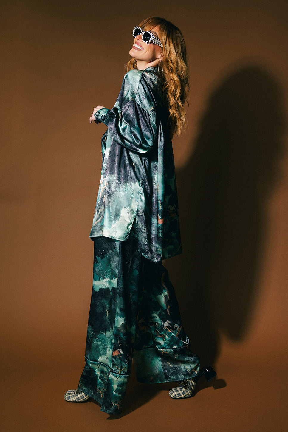 Person wearing an emerald satin set with a mountainous design and mustangs against a brown background