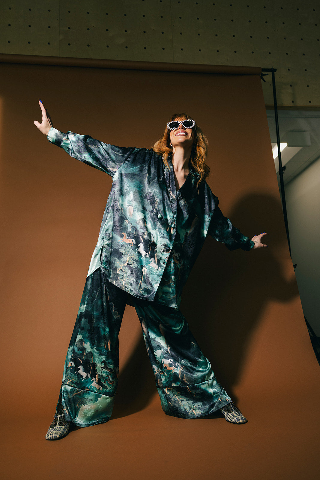 Person wearing an emerald satin set with a mountainous design and mustangs against a brown background