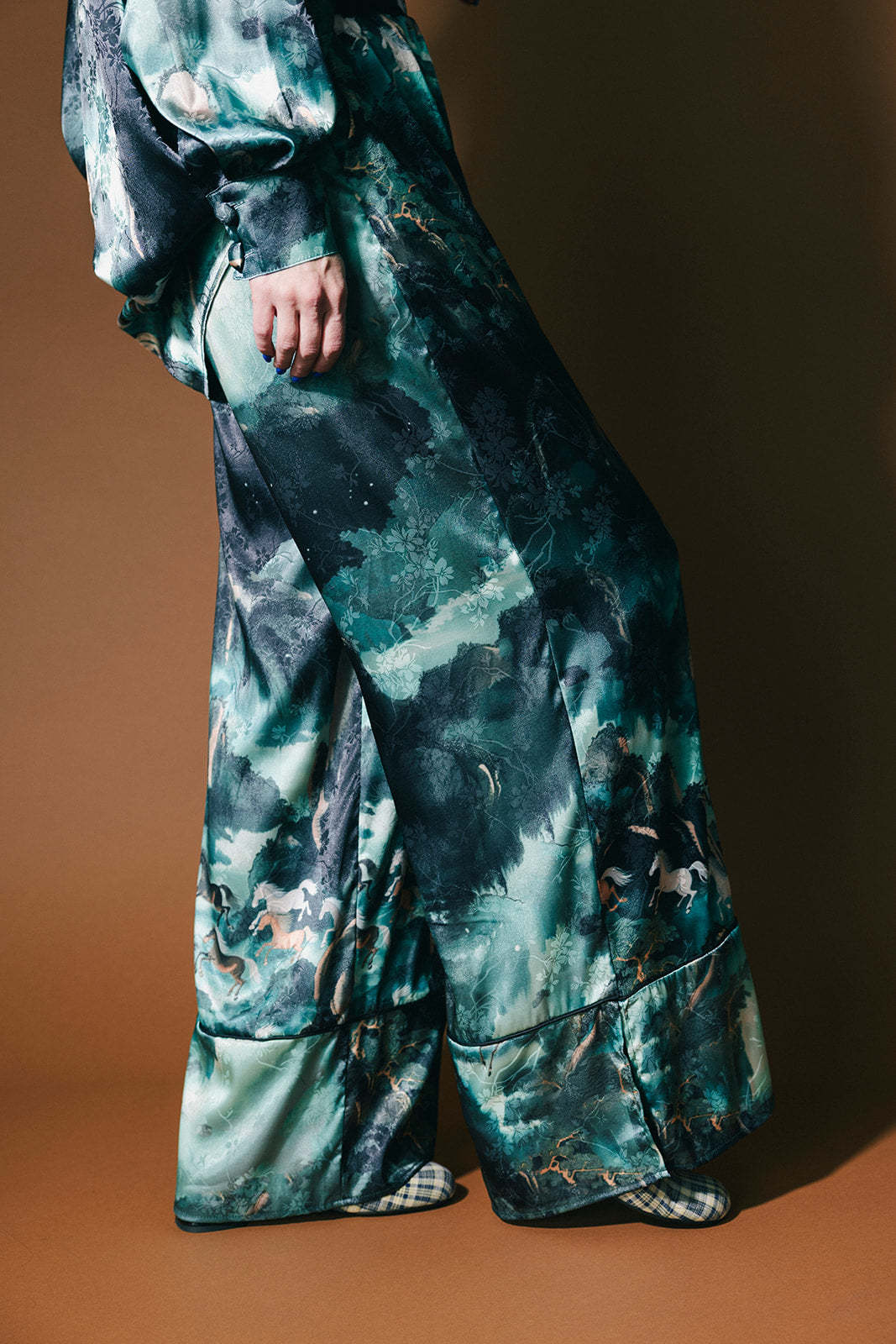 Person wearing an emerald satin set with a mountainous design and mustangs against a brown background
