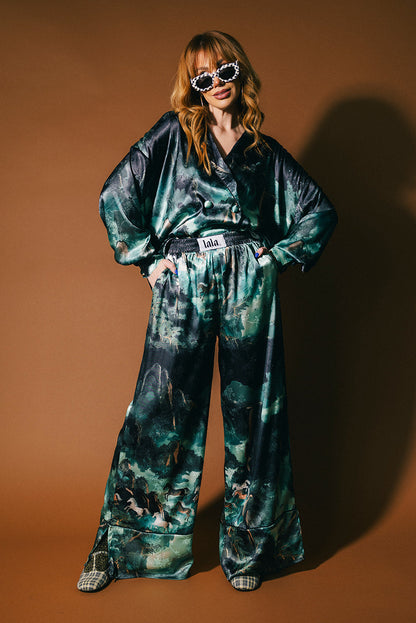 Person wearing an emerald satin set with a mountainous design and mustangs against a brown background