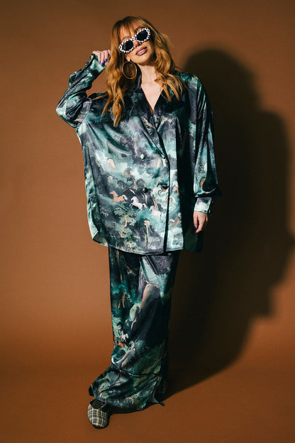 Person wearing an emerald satin set with a mountainous design and mustangs against a brown background