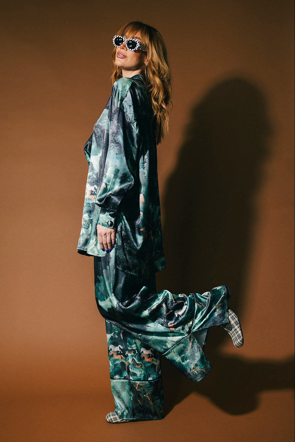 Person wearing an emerald satin set with a mountainous design and mustangs against a brown background