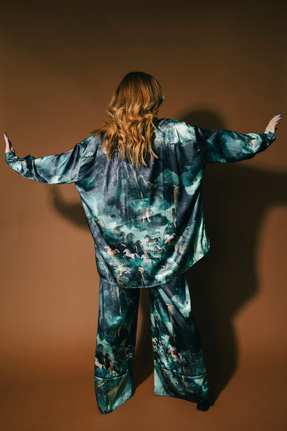 Person wearing an emerald satin set with a mountainous design and mustangs against a brown background