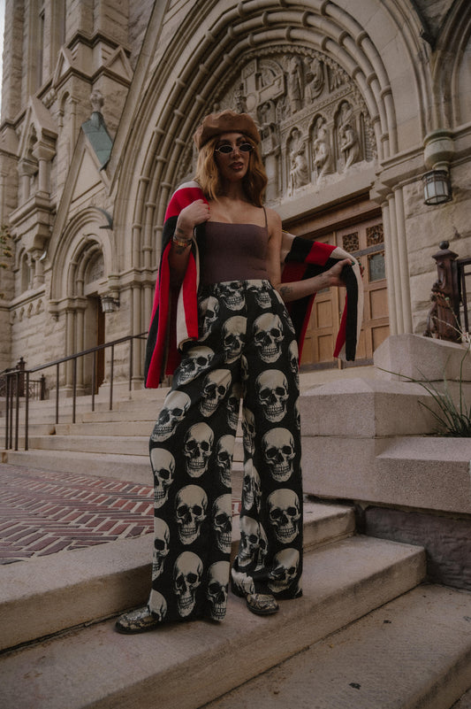 Person wearing skull-patterned trousers in front of a cathedral.