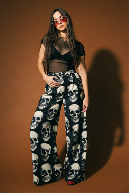 Woman wearing skull-patterned trousers against a brown background