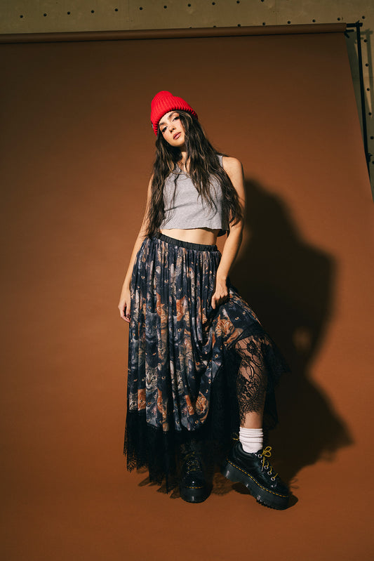 Woman wearing a cat pattern mesh skirt with lace hem against a brown background.