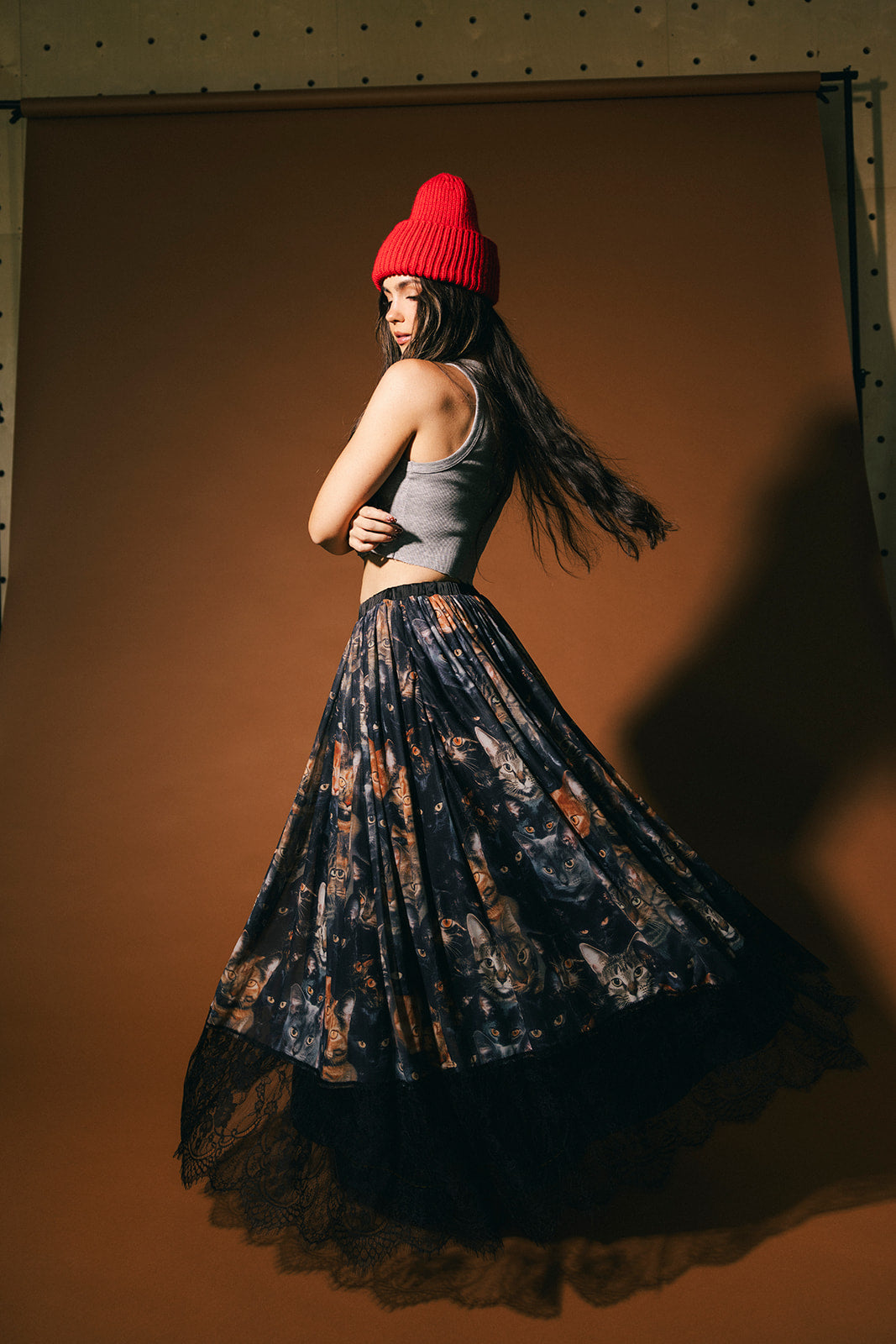Woman wearing a cat pattern mesh skirt with lace hem against a brown background.