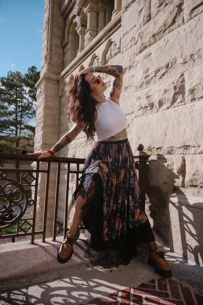 Woman posing on a balcony with a stone building in the background wearing a cat pattern mesh maxi skirt with lace hem.