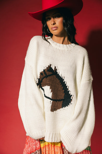 Woman wearing a white sweater with a horse design against a red background