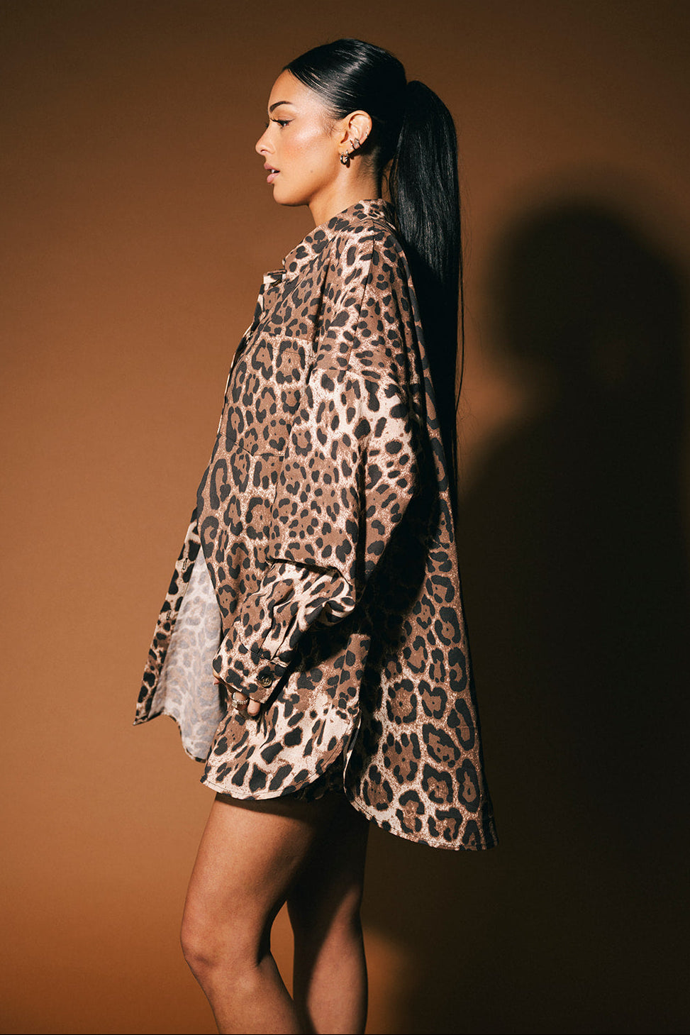 Woman wearing a leopard print outfit against a brown background
