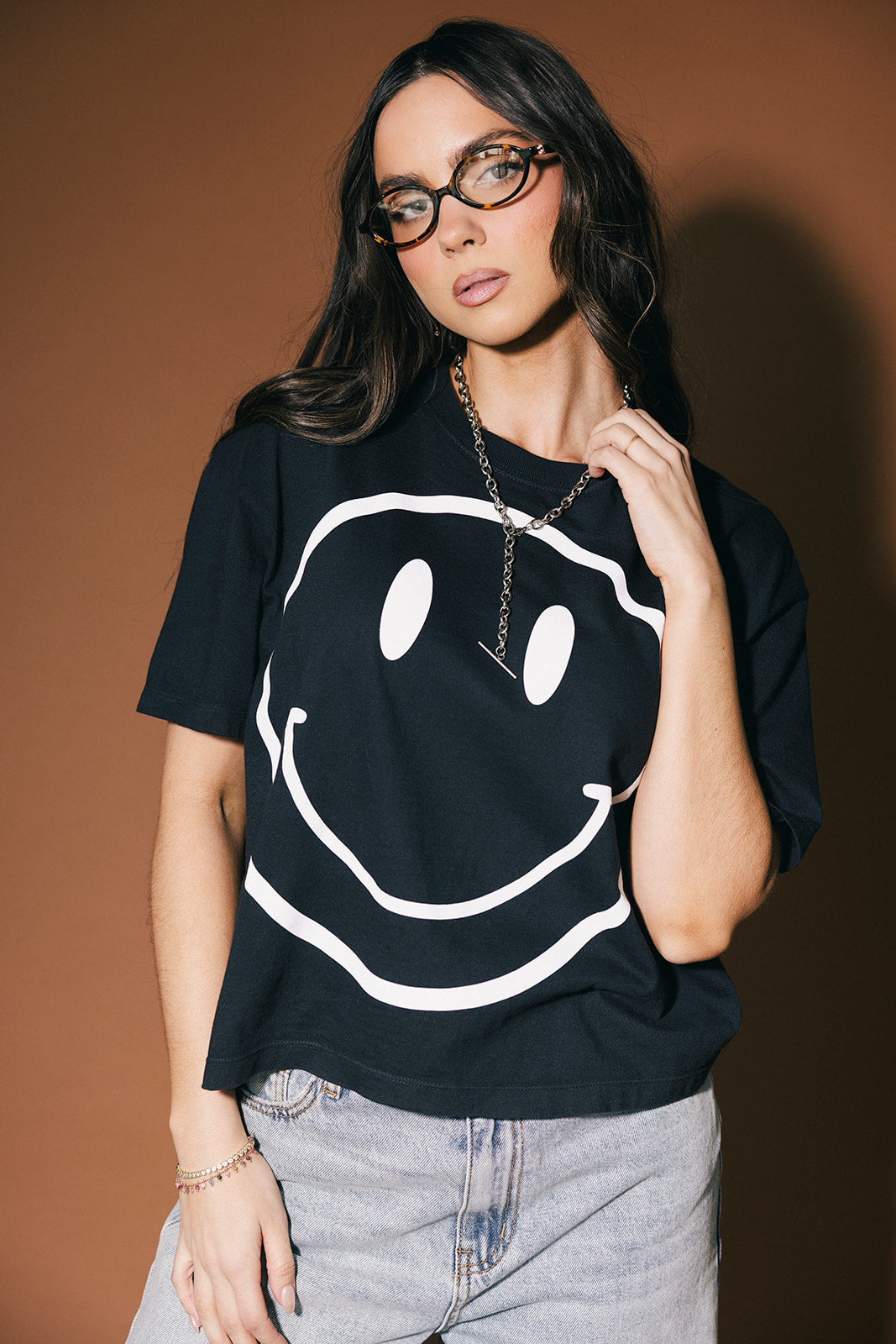 Woman wearing a black t-shirt with a white smiley face design on a brown background