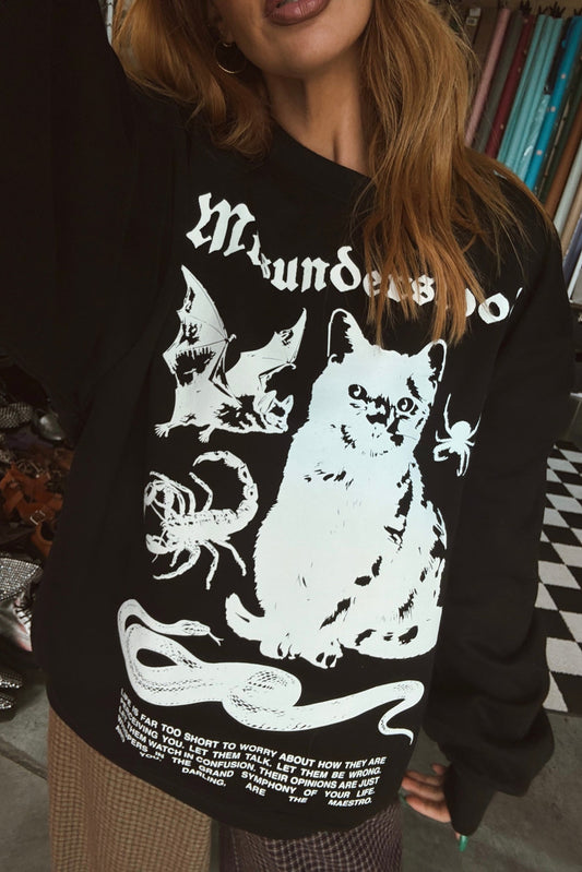 Person wearing a black sweatshirt with white graphic design of a cat, scorpion, and other elements.