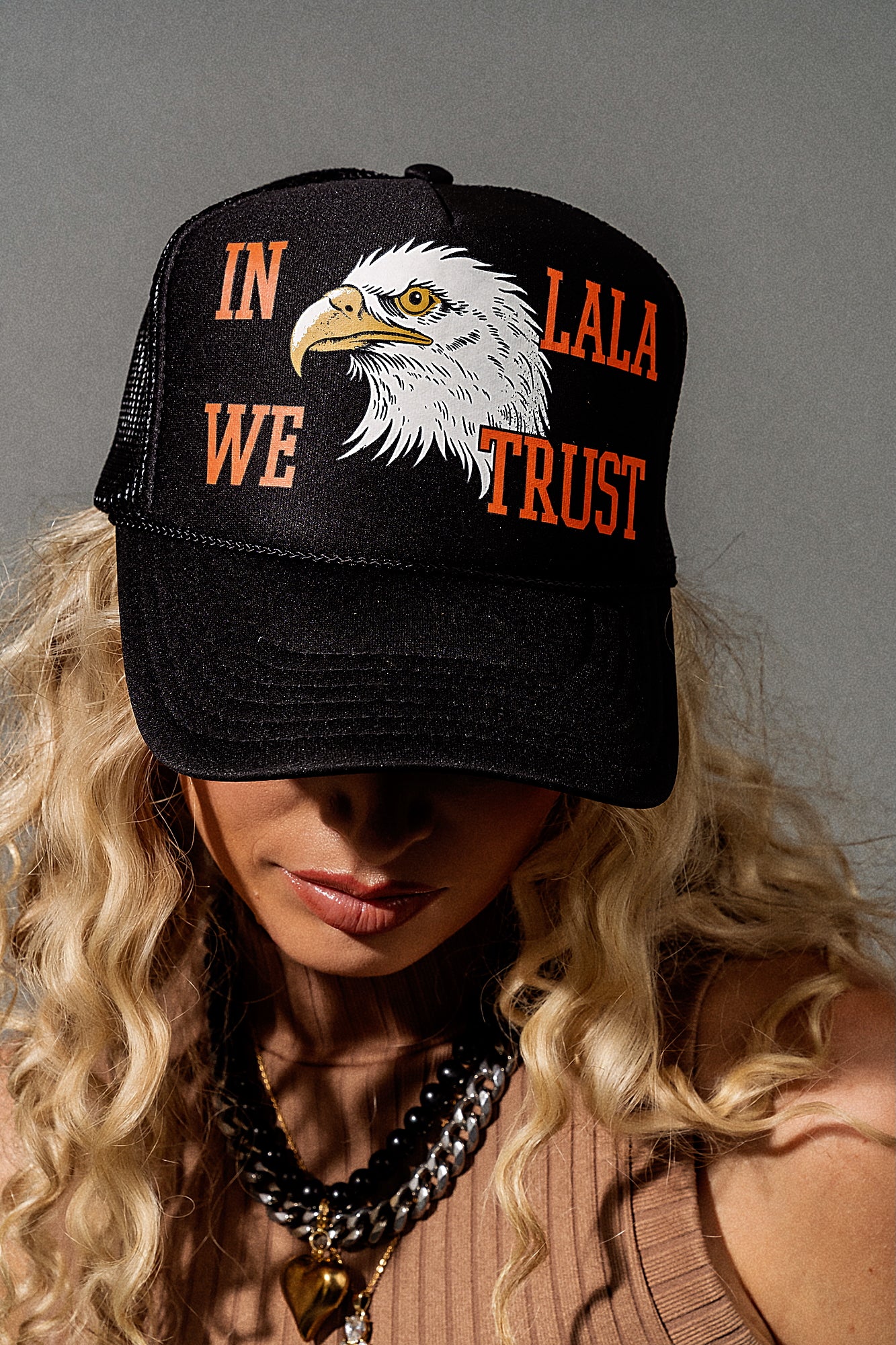 Person wearing a black cap with an eagle design and text against a gray background