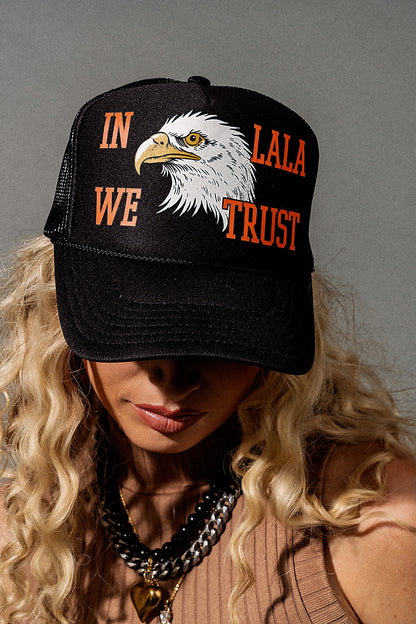 Person wearing a black cap with an eagle design and text against a gray background