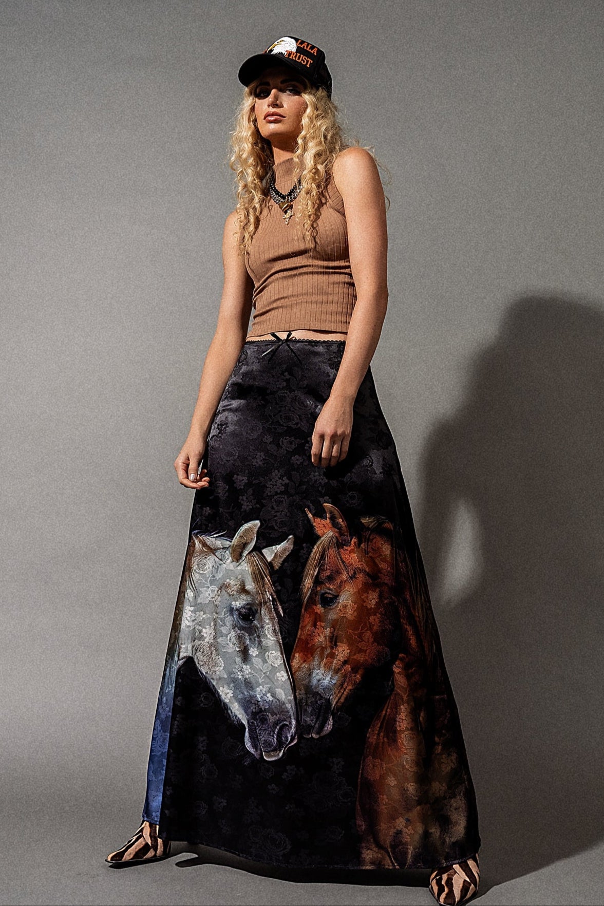 Woman wearing a long skirt with horse designs against a gray background