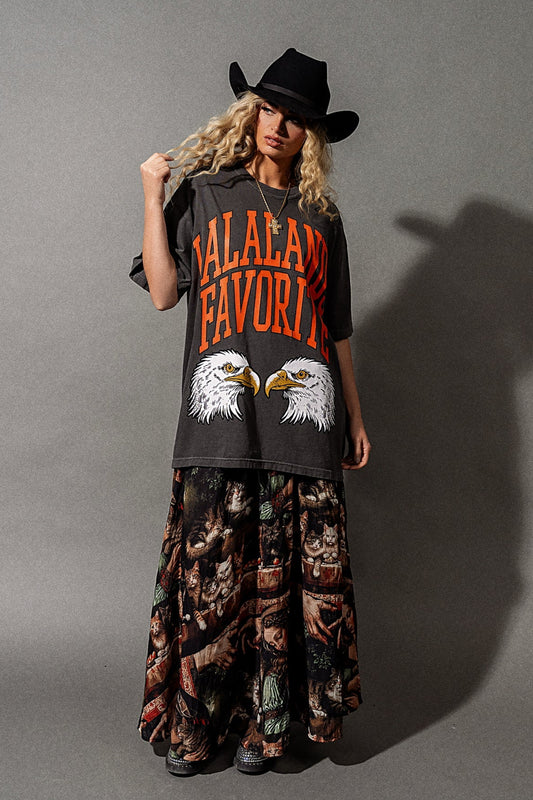 Person wearing a graphic t-shirt with text and images, standing against a gray background