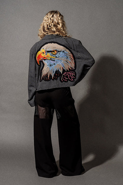 Person wearing a jacket with an eagle design on the back against a gray background