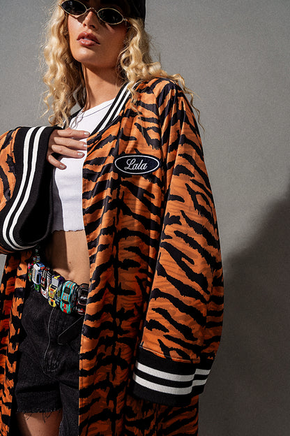 Person wearing a tiger-striped jacket with a brand logo on a gray background