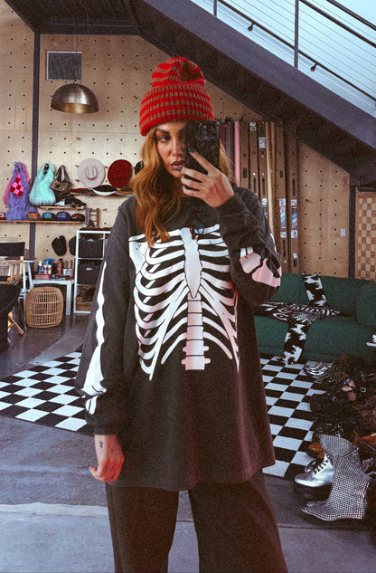 Person wearing a red beanie and skeleton-patterned shirt in a room with checkered floor and staircase.