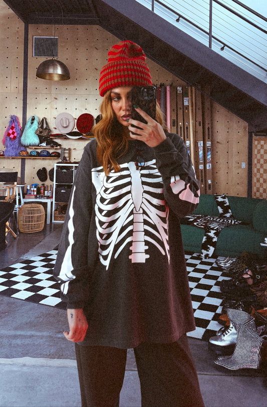Person wearing a red beanie and skeleton-patterned shirt in a room with checkered floor and staircase.