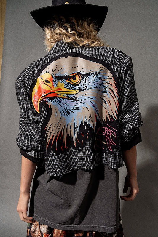 Person wearing a blazer with an eagle design on the back against a gray background