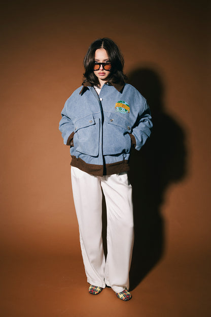 Person wearing a blue denim jacket with a logo on a brown background