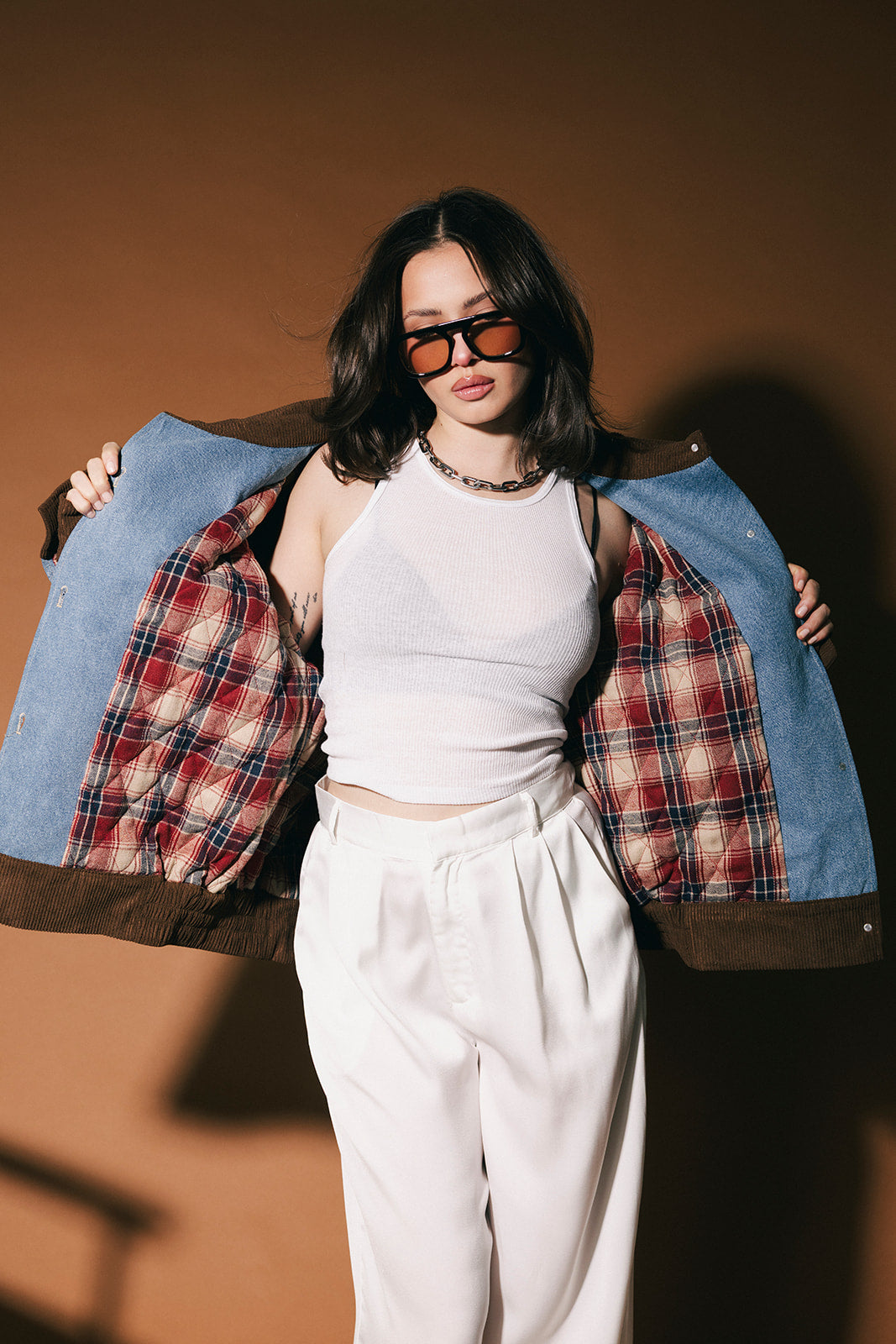 Woman holding a denim jacket open showing the quilted flannel lining against a brown background