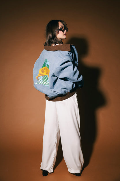 Person wearing a blue denim jacket with a logo on a brown background