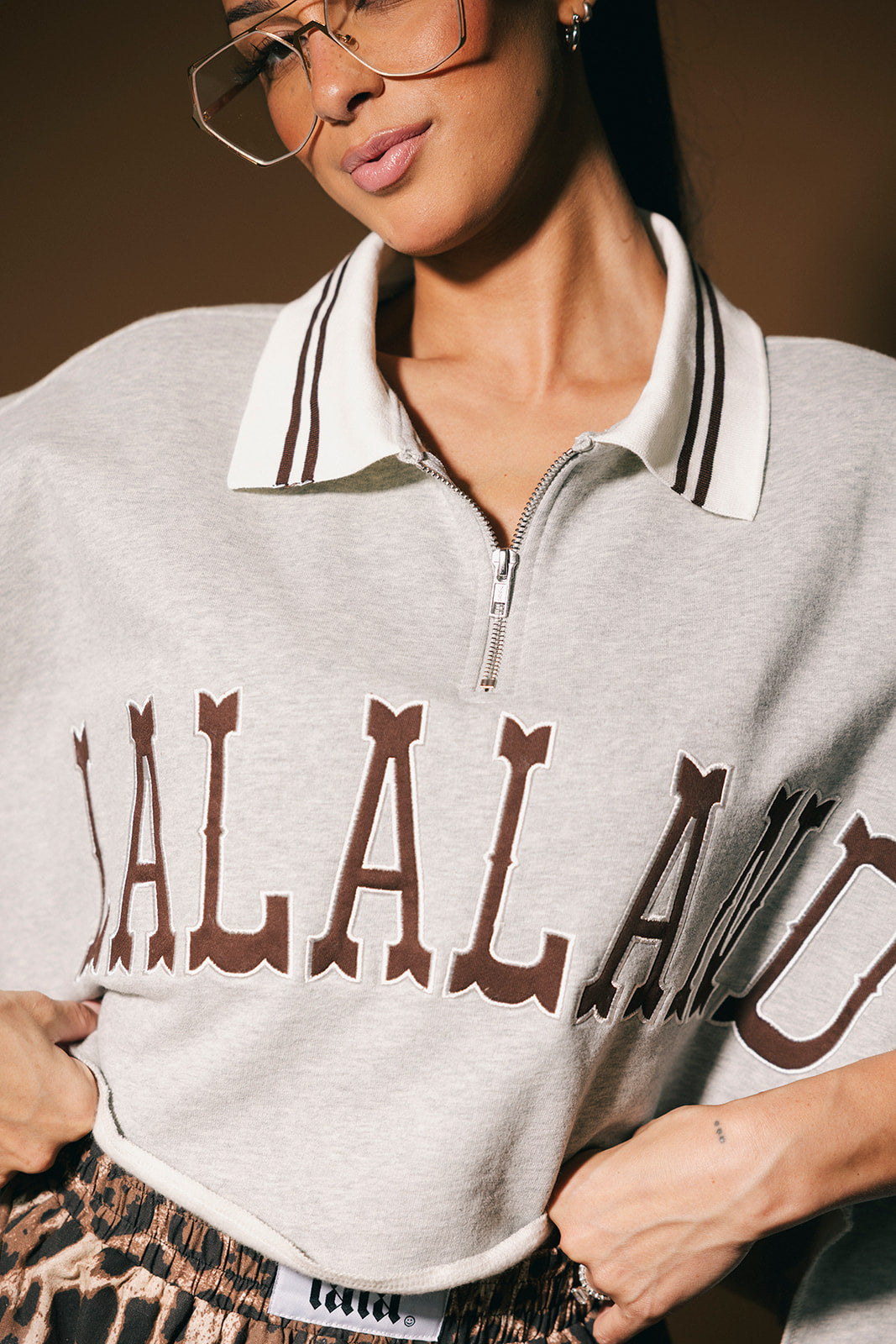 Person wearing a gray polo with 'LALALAND' text, standing against a neutral background