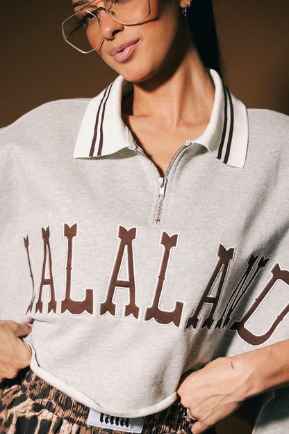 Person wearing a gray polo with 'LALALAND' text, standing against a neutral background