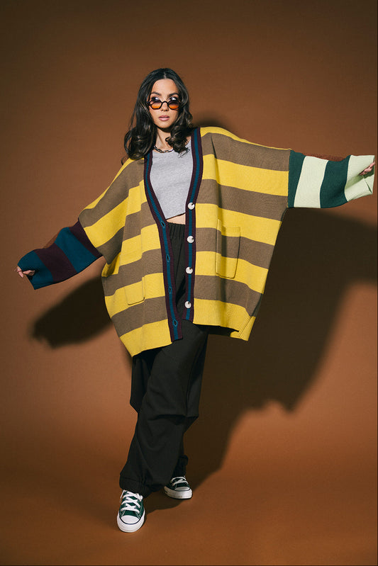 Person wearing a colorful striped cardigan on a brown background