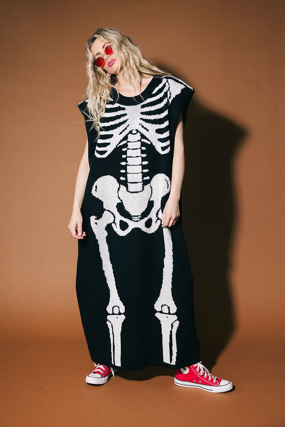 Person wearing a black dress with a white skeleton design against a brown background