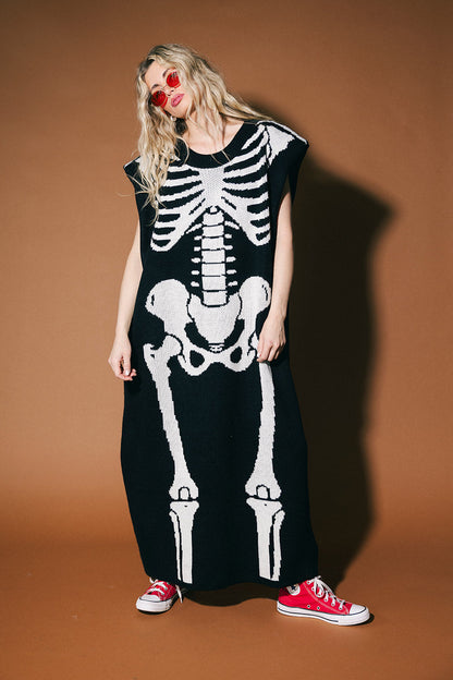 Person wearing a black dress with a white skeleton design against a brown background